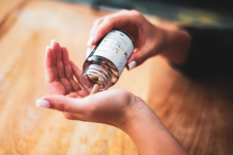 Woman taking Liver Complex capsules from bottle